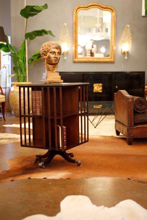 English Edwardian solid mahogany revolving bookcase on quadripode base with gilt bronze claw feet hiding steel casters. Original green embossed and gold leafed leather top.