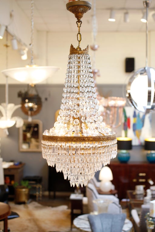 French antique pair of Empire style crystal and brass chandeliers, complete with matching antique chain and canopies.