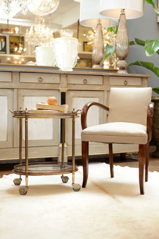 French antique brass side table on casters with two removable trays, the top clear glass and the bottom antiqued mirrored glass, both surrounded by a finely detailed brass gallery. Fluted legs, acorn finials, and handles on the top tray. The brass