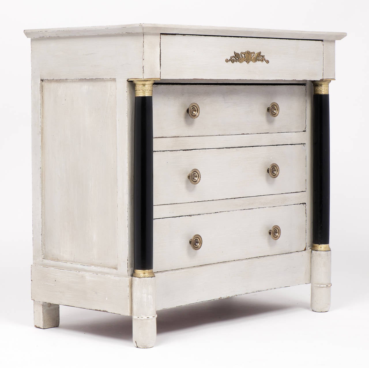 Antique French Empire style chest of drawers with swan bronze detail, four dovetailed drawers, and two ebonized columns with finely cast brass capitals. Superb craftsmanship, proportions. We could not resist the decorative impact.