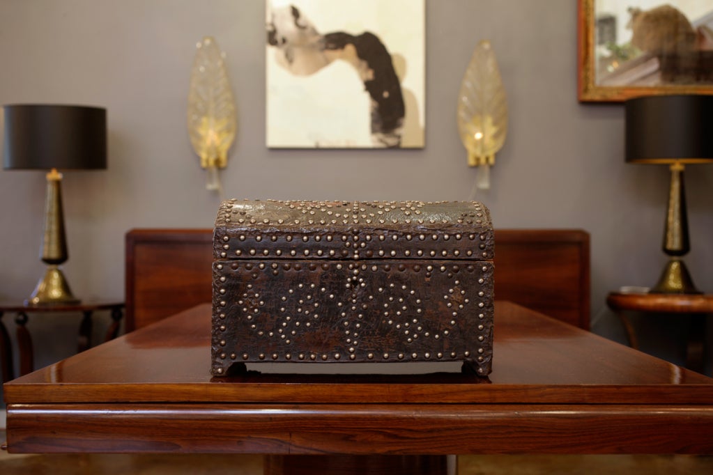 An antique leather covered box with decorative studs.