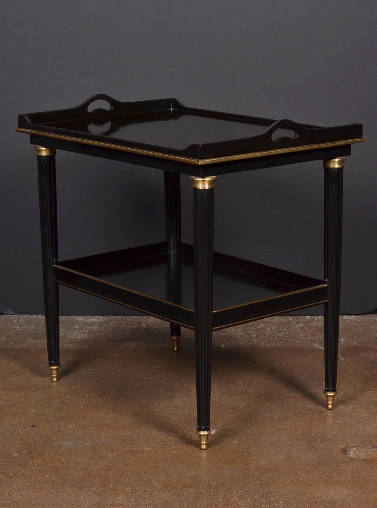 Antique French Louis XVI style tea table in ebonized mahogany, finished with a gleaming French polish and brass trim, with fluted and tapered legs.