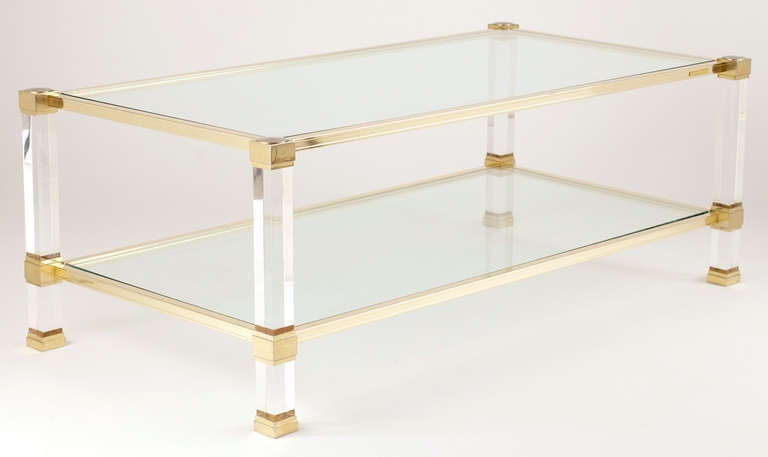 French mid-century coffee table with brass corners, feet, and frames; lucite legs; and glass top & bottom shelves. Signed Pierre Vandel Paris.