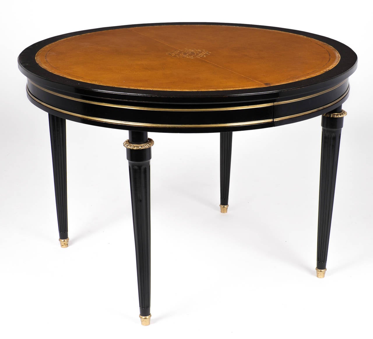 French antique Louis XVI style dining table in ebonized mahogany with a lustrous French polish finish, ormolu details, brass trim and fluted legs. The lovely tan leather top is embossed with gold leaf. Perfect for use as a small dining table, game