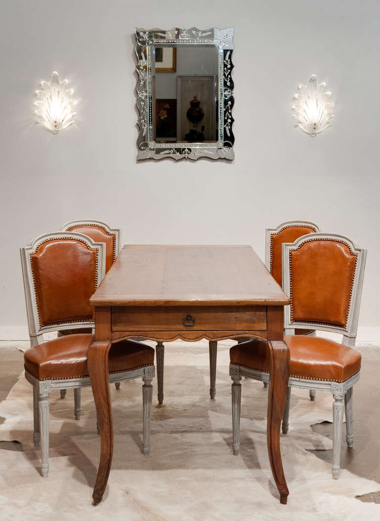 Wonderful set of Louis XVI style dining chairs (two armchairs and four side chairs) with hand-carved and gray patined frames and original leather upholstery. Measurements in listing are for the side chairs. By Maison Hirsch (Maison Hirsch