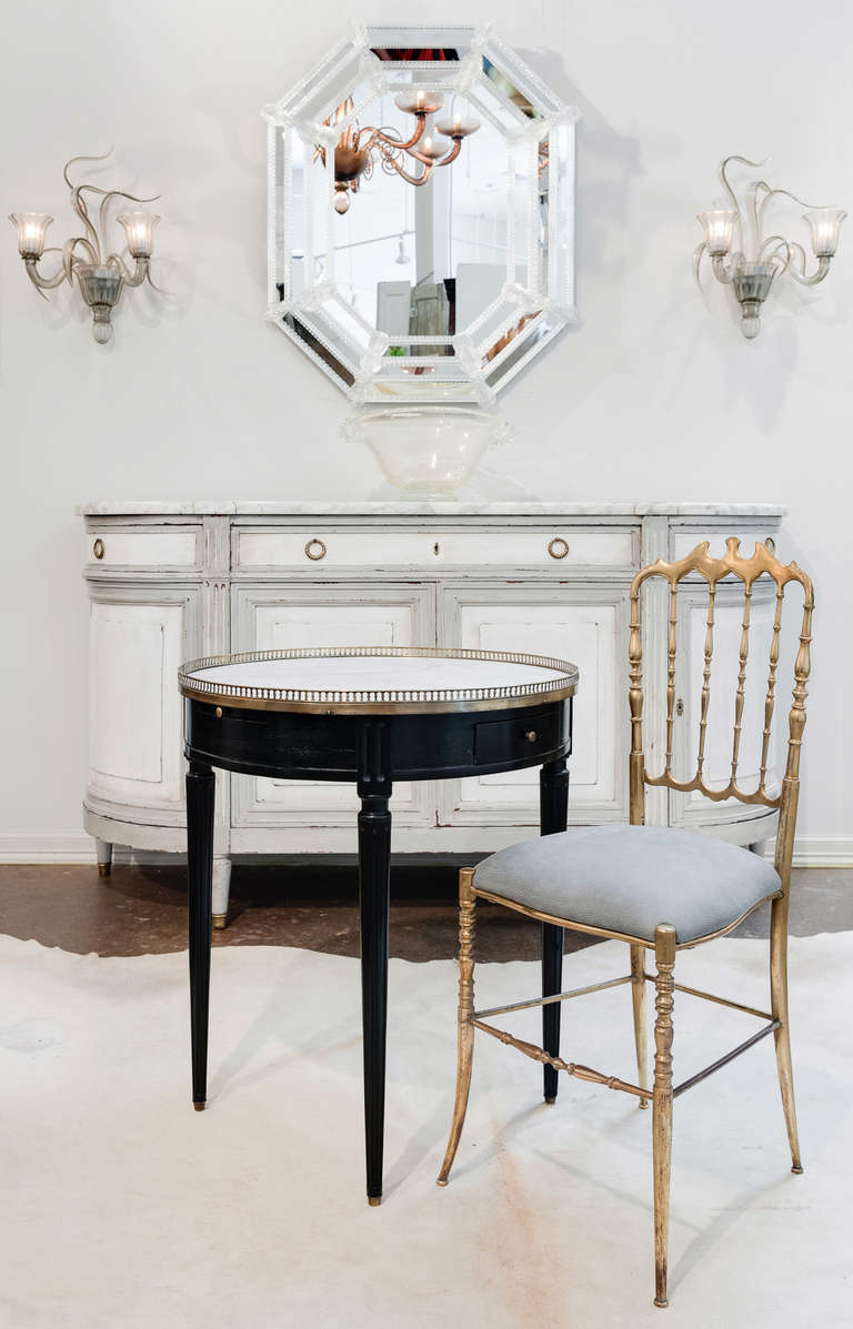 French Louis XVI style solid mahogany ebonized and French polished bouillotte table with a Carrara white marble top surrounded by a finely cast brass gallery. Two pull out trays and two dovetailed drawers with brass pulls. Fluted legs capped with