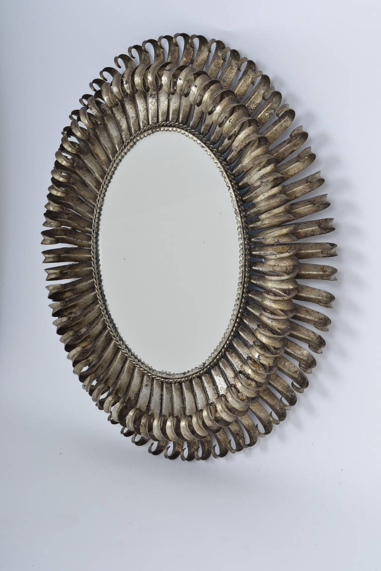 French vintage sunburst mirror with original, beveled, oval glass mirror, framed by silver-leafed hand-embossed metal (tin) with scalloped edge, braided rope detail, and two layers of curving metal sunburst rays. Reminiscent of the works by