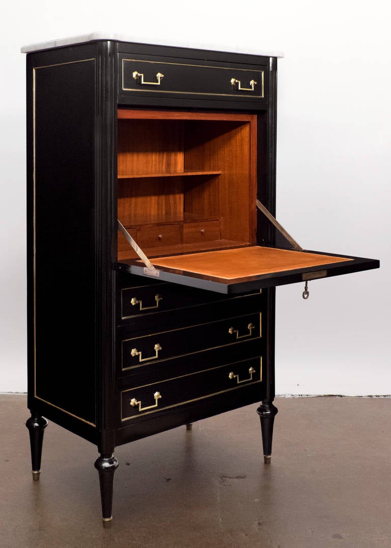French antique Louis XVI style secretaire in solid mahogany, ebonized and French polished, with a Carrara marble top, brass hardware and trim, hand embossed and gilded leather, carved fluted details. This secretary has four dovetailed drawers and a