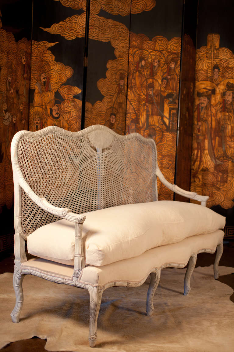 Rare 1900 French sofa in the manner of Maison Jansen, caned back, hand carved frame with rope detail, upholstered with off-white soft canvas-like cotton blend, white goose down fill. Elegant and unique piece for your den or sun room. Strong and