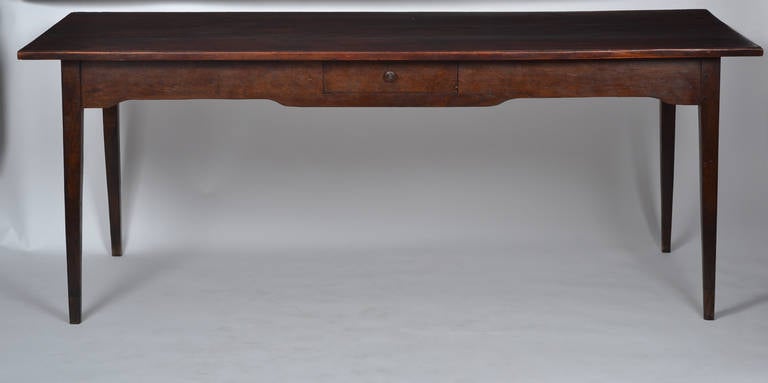 French farm table of fir wood with a drawer, tapered leg and plank top. These pieces were the essential piece in humble French farm house kitchens. We love the proportion and patina on this one.