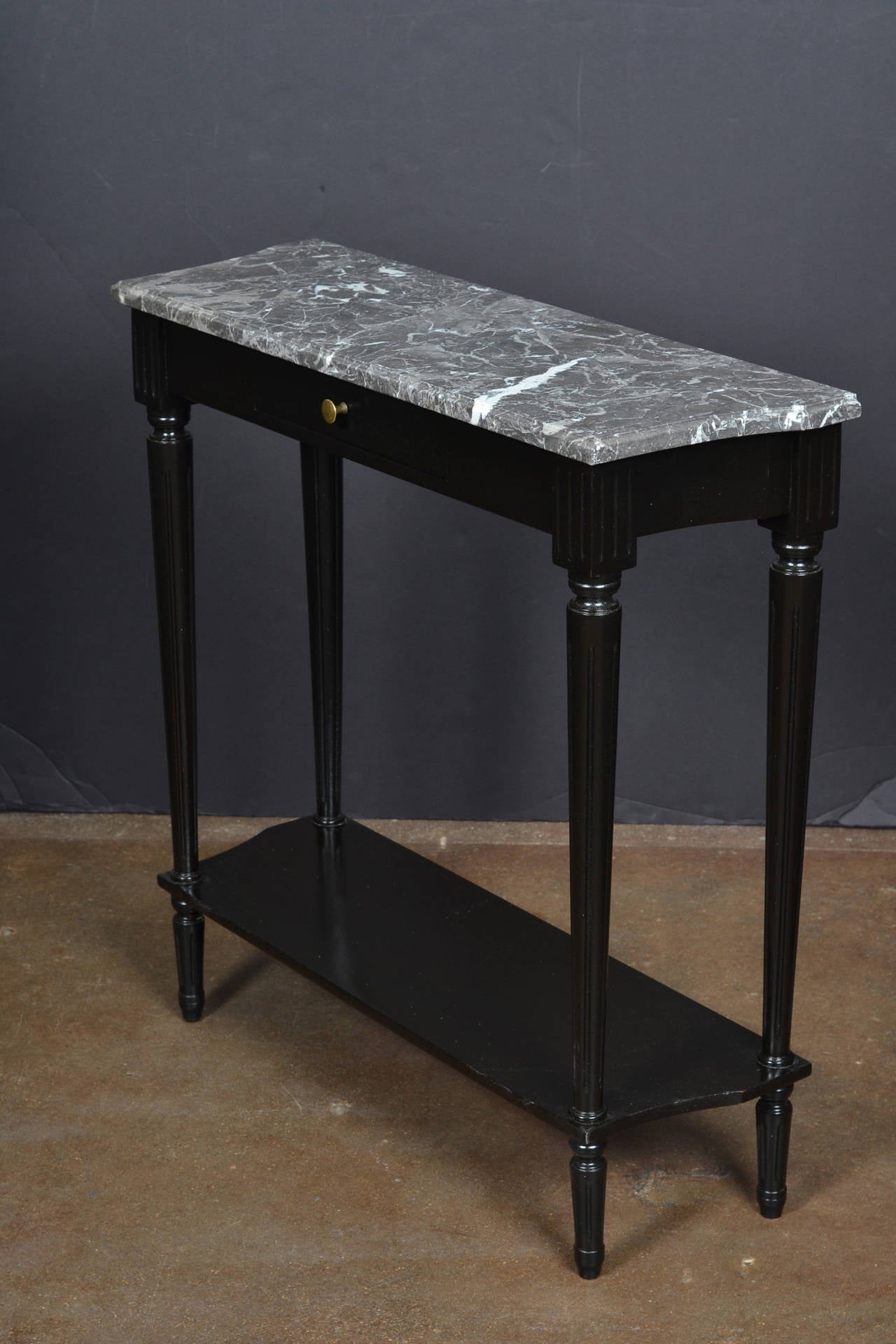 French Louis XVI style console table, ebonized with a lustrous French polish finish, topped with Saint Anne marble. A single dovetailed drawer has a brass pull, plus a bottom shelf. Elegant, versatile and timeless design.