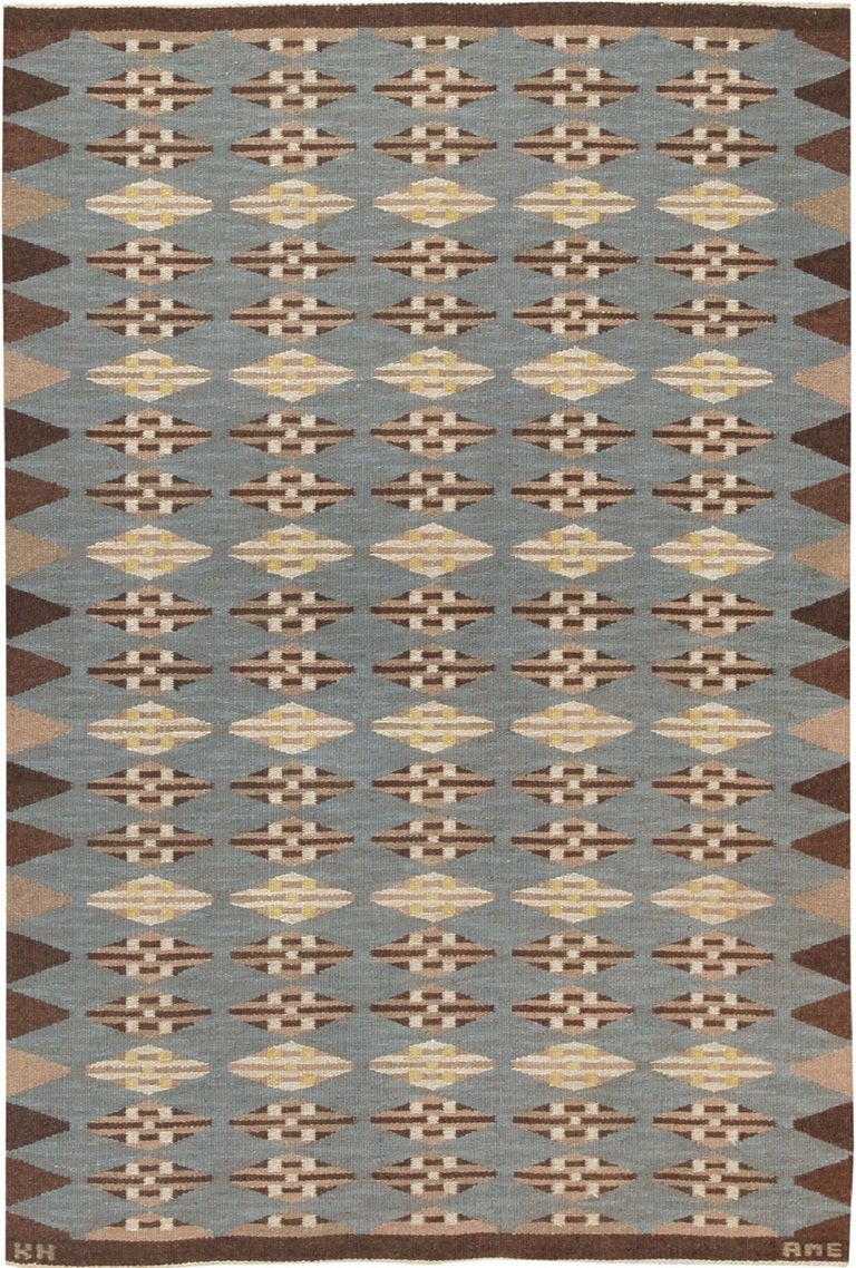 This striking mid-century Modernist rug was created by a regional crafting society called Klockaregardens Hemslojd in the Swedish village of Tallberg.  A pleasing diamond motif plays across the slate blue field, accented by shades of beige and