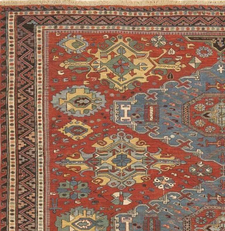 Created in the Caucasus, this elegant antique Soumak rug features a sophisticated composition with grand stacked medallions surrounded by minor motifs. The beautifully oxidized crimson field is dotted with constellated symbols and botanical motifs
