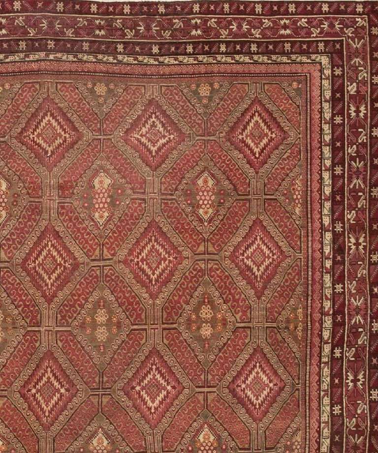 This exquisite antique carpet created in Agra features a sublime latticework pattern with octagonal cells linked by continuous lines. Serrated lozenges with extended pendants and scrolling outlines decorate rows of tiles alternating with oxidized