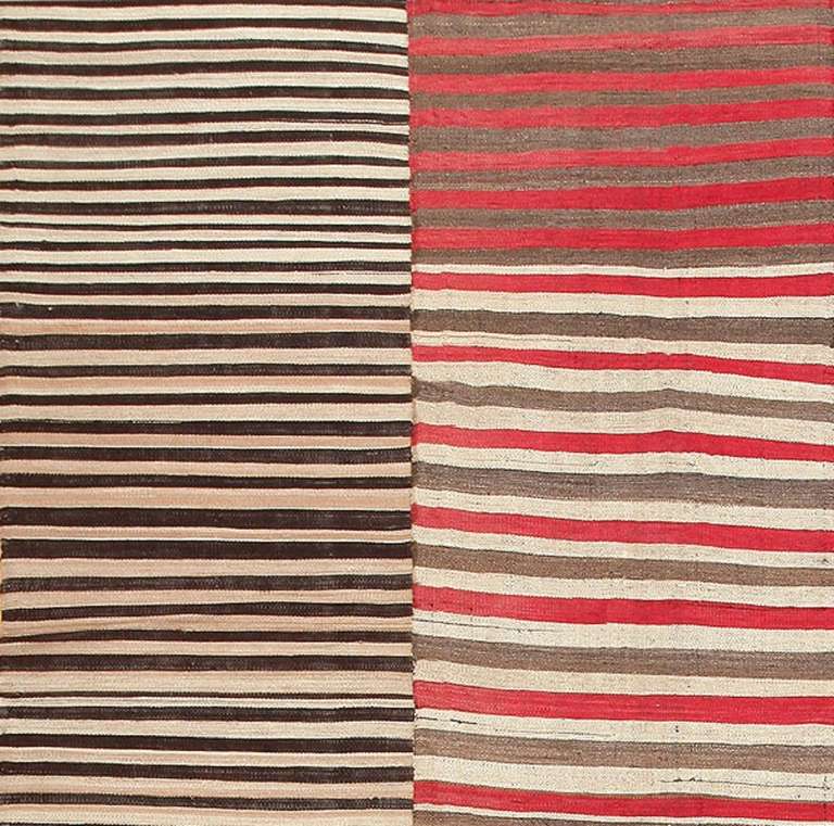 This brilliant antique Persian Mazandaran Kilim artfully explores the wonders of color, texture and perception through a simple pattern of flat-weave stripes. Dark black-and-white stripes occupy alternating panels, creating a somber bark-like effect