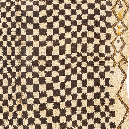 This outstanding Mid-century Moroccan rug showcases a captivating ebony and alabaster checkerboard pattern that covers the majority of the richly textural field. The gradient background transitions from a neutral hue of ivory to a bold hue of
