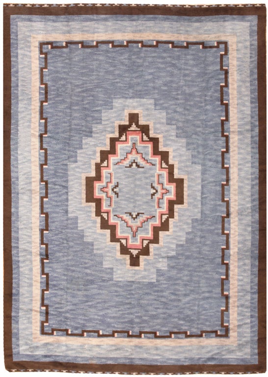 This phenomenal vintage Swedish rug features a dramatic Minimalist composition that bridges the gap between traditional styles and the first modern trends. The textural periwinkle field showcases a radiant stepped-lozenge medallion set over a rich