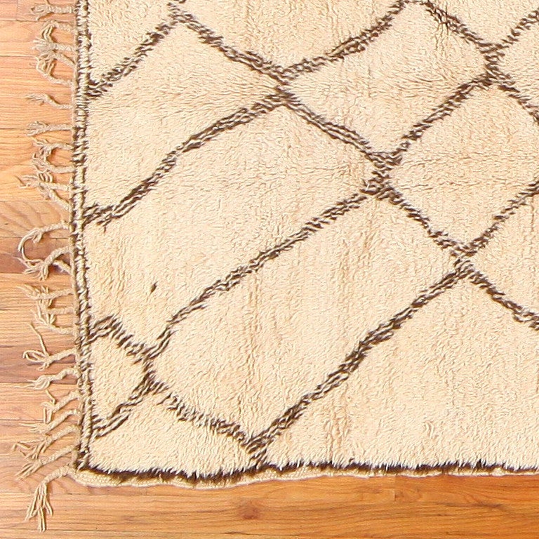 Vintage Moroccan rug, circa mid-20th century. This vintage Moroccan rug is an intriguing mid 20th century Moroccan carpet. It is a very beautifully designed rug that contains a soft ivory background with a rich dark brown Moroccan abstract pattern.