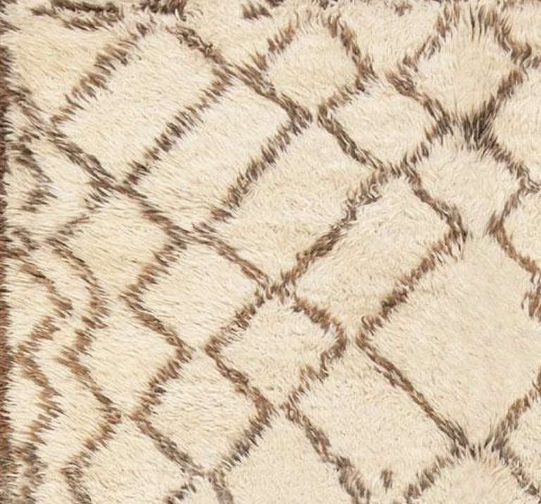 Created in Morocco, this sumptuous vintage rug features luxurious textural pile and a naturally minimalist color scheme. Muted chamoisee brown patterns and geometric glyphs incorporate warm fleecy browns and subtle color variations set over a chic
