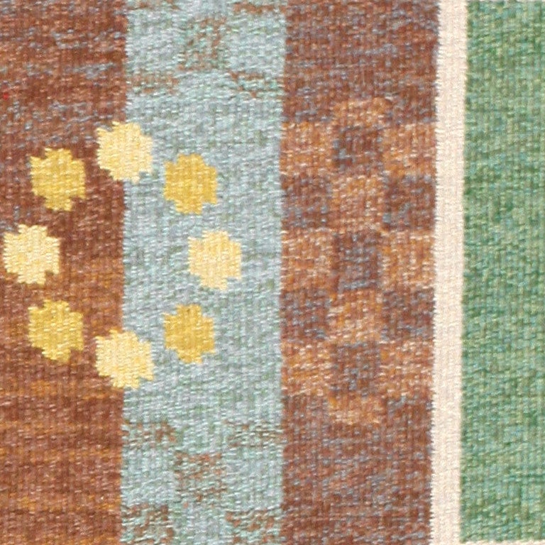 Vintage Swedish Kilim, circa mid-20th century. Carl Dagel brings us a rustic vintage Swedish rug in a cozy palette of browns, greens, and light blues, offset by neutral accents. This design juxtaposes circular and rectangular shapes, indicating a