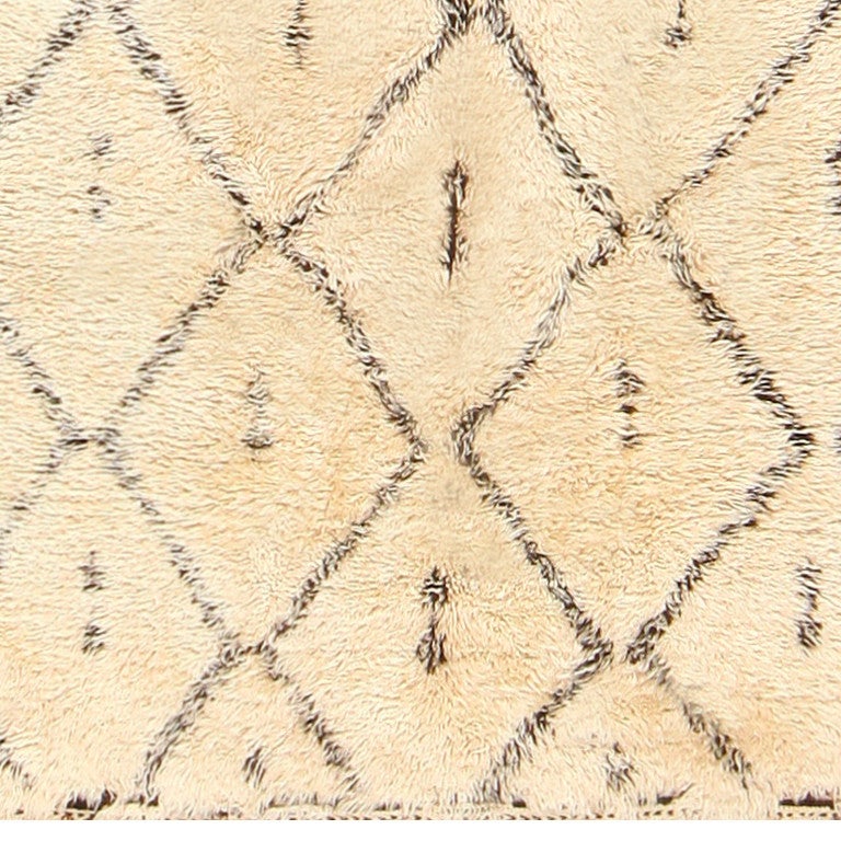 Vintage Moroccan rug, circa mid-20th century. This classic vintage Moroccan rug features a ivory base, set under a black theme that evokes tribal influence and Minimalist design. The rudimentary diamond structure, coupled along with generous