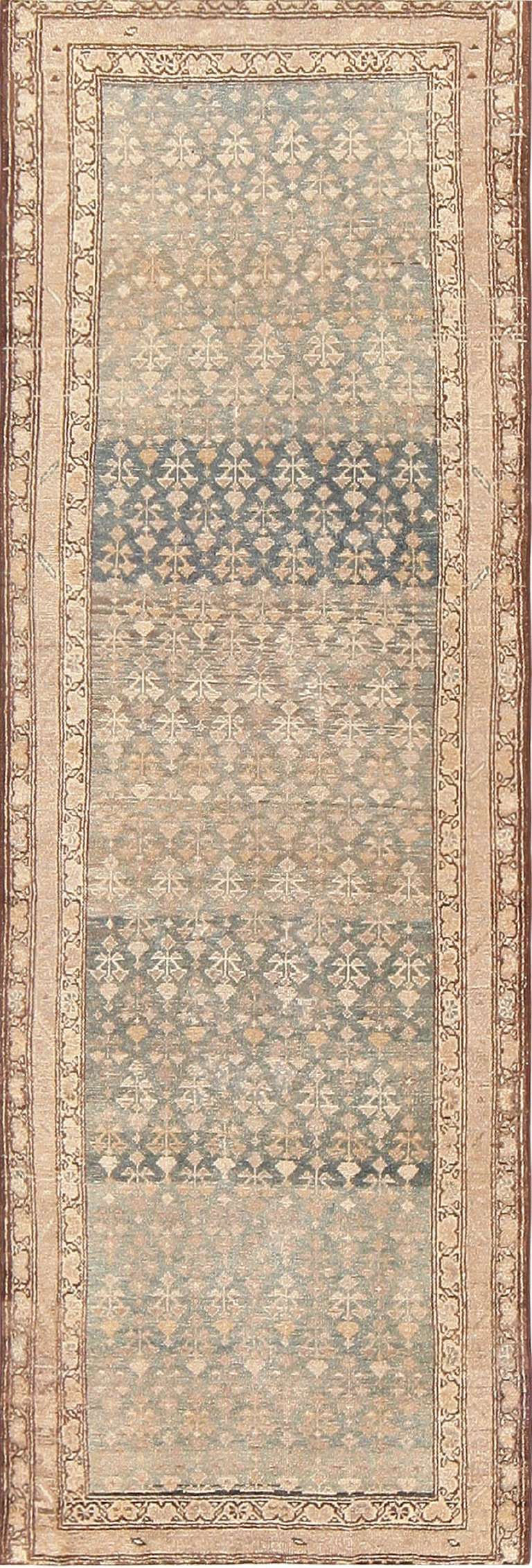 Here is a wonderful antique Persian Malayer runner, composed of a subdued pallet of of soft golds and blues. A quiet allover design of repeating floral elements, woven in soft gold tones against the blue field, give this Persian rug a characteristic