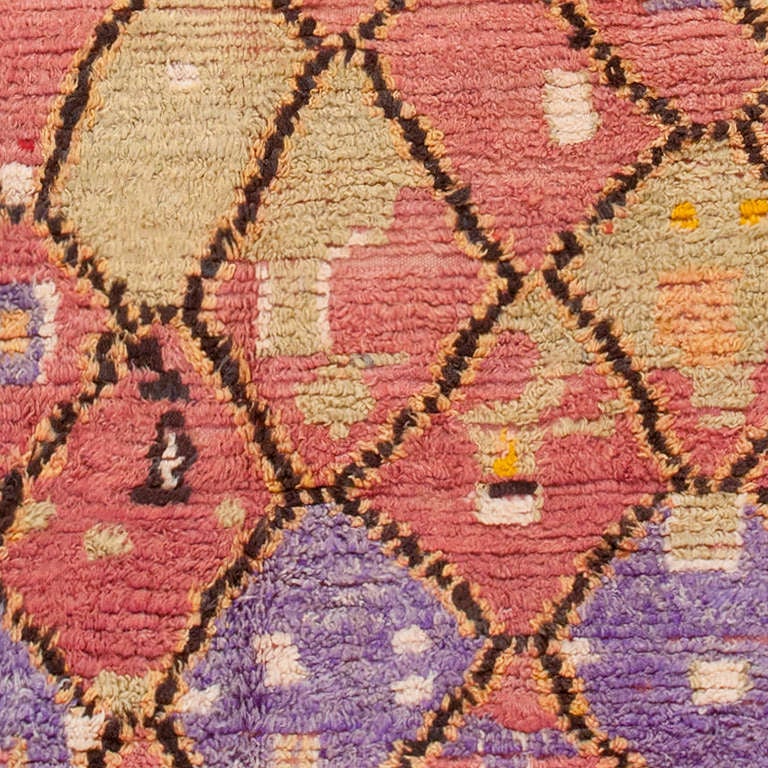 Woven in the mid-20th century, this colorful Moroccan rug features richly textured pile, strong designs and a contrasting color palette, including various shades of rose pink, electric purple, celadon, orange and Kohl black. Bright orange and