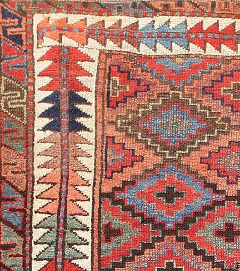 Here is a particularly fetching antique Oriental rug - an antique tribal Kazak rug, hand woven by the great rug makers of the Caucuses. This particular example, which is of runner proportions, is characterized by its colorful, geometric field, which