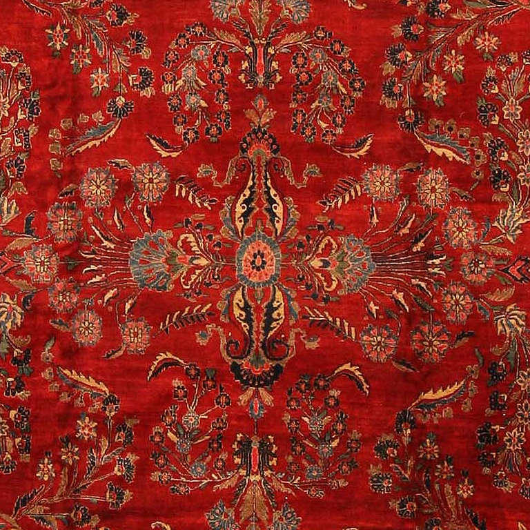 Antique Sarouk, Persia, early twentieth century - Graceful spays of swaying, flowering vines repeat in allover symmetry across the warm red field of this sumptuous antique Sarouk from Persia. The palette of soft blues and ivory appears especially