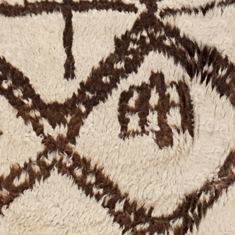 Moroccan rug, Morocco, mid-20th century. This stately vintage rug from Morocco features a complex latticework pattern embellished with ancient symbols and boldly drawn motifs rendered in a striking high-contrast combination of ivory and deep walnut