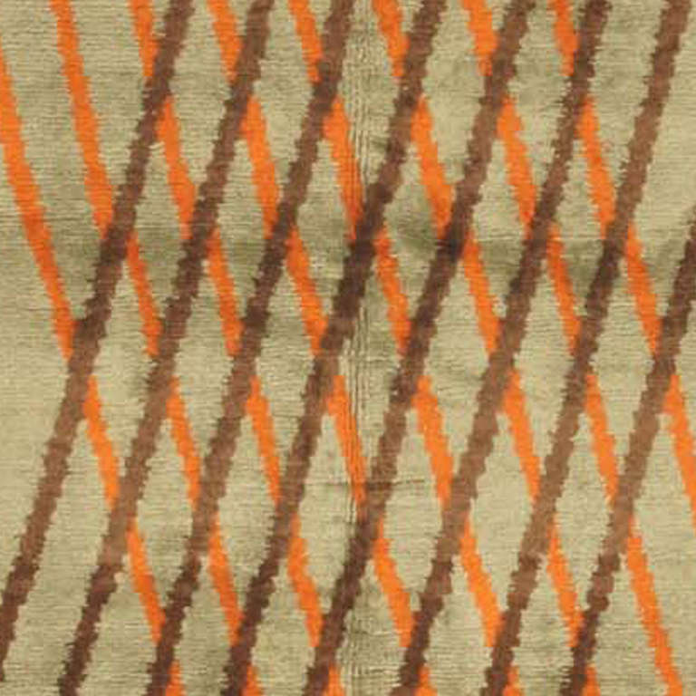 This imposing Art Deco carpet is the epitome of Modernist sophisticated simplicity. Intersecting diagonal lines in brown a apricot perform a chiastic dance across the open silver-grey surface. The brilliance of the design is matched by the brilliant