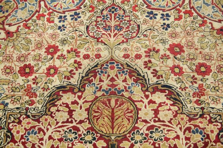 A dazzlingly complex lace-like medallion of classical Persian derivation spreads across the field of this elegant antique Kerman. The medallion is framed by cornerpieces made up of swirling vines, while sprays of flowers serve as finials at its