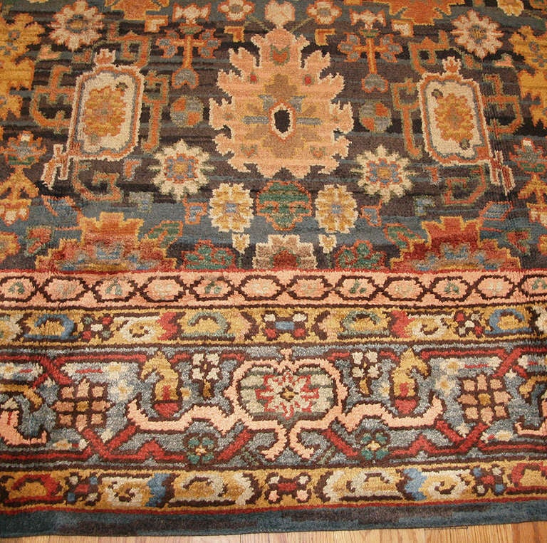 This antique Donegal Irish rug from Ireland depicts a dignified Indo-European blossom pattern executed in a splendid combination of traditional warm and cool colors. Deeply notched palmettes, ornamental rosettes and elaborate Harshang motifs dot the