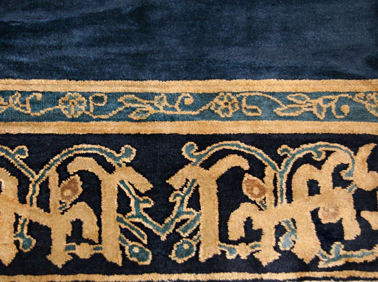 This superb antique Chinese rug features an expansive monochromatic royal blue field that is paired with elaborate Indo-Persian borders. Elegant inner borders adorned with a meandering pattern of graceful vine scrolls perform a transitional function