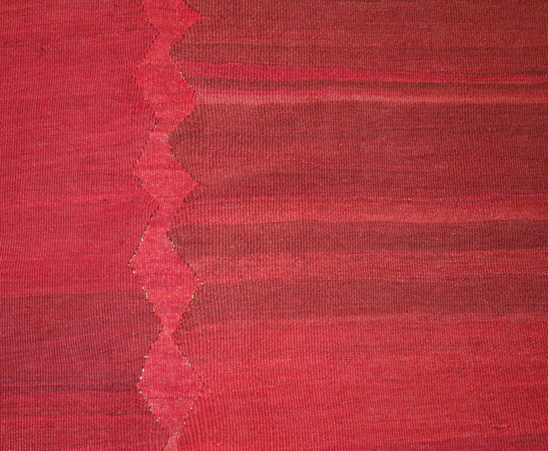 Undiscovered in the West until the end of the 20th century, this antique Persian Mazandaran kilim is a pre-modernist gem full of color and minimalist detail. This spectacular creation displays an explosive selection of saturated cerise, cherry reds