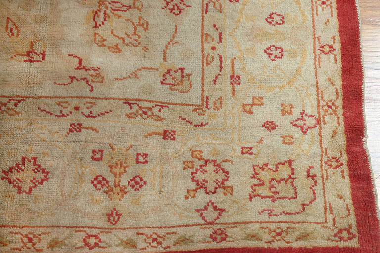 This antique Oushak is a symphony of luscious cream and tan tones accented with sparing linear detail in red. One might easily think that this detail largely comprises the pattern, but a closer look reveals the intervening design in tan on cream.