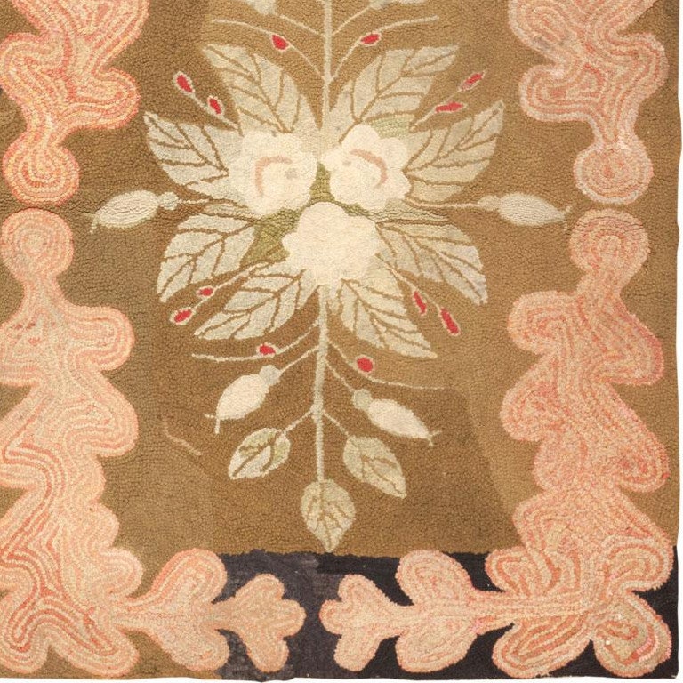 Created circa 1910, this charming antique American hooked rug features an elegant bouquet surrounded by a border of undulating oak leaves decorated with concentric details. The informal borders feature marbled accents that emphasize the charming