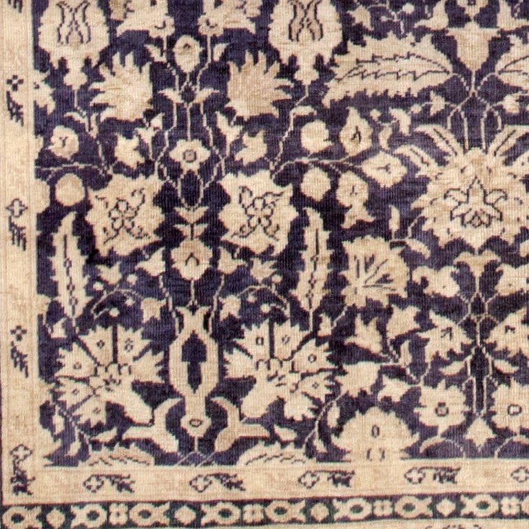 Woven in the 1910s, this antique Turkish carpet features a chic combination of taupe and midnight blue along with elegant curvilinear patterns that flow with the ease of a traditional Safavid design. Small-scale guardbands and taupe main borders