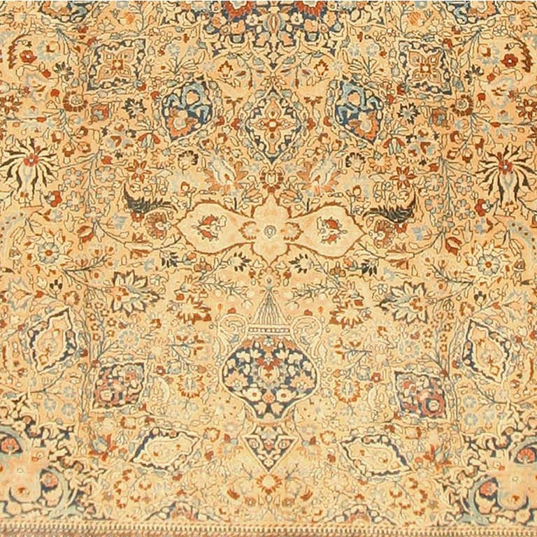 A delicate, almost lace-like design of small flowers, fine vines, and palmettes in blues, cinnamon, and pale apricot sprawls gently across the light tan field of this exquisite antique Khorassan. This sumptuous array of forms is organized as a