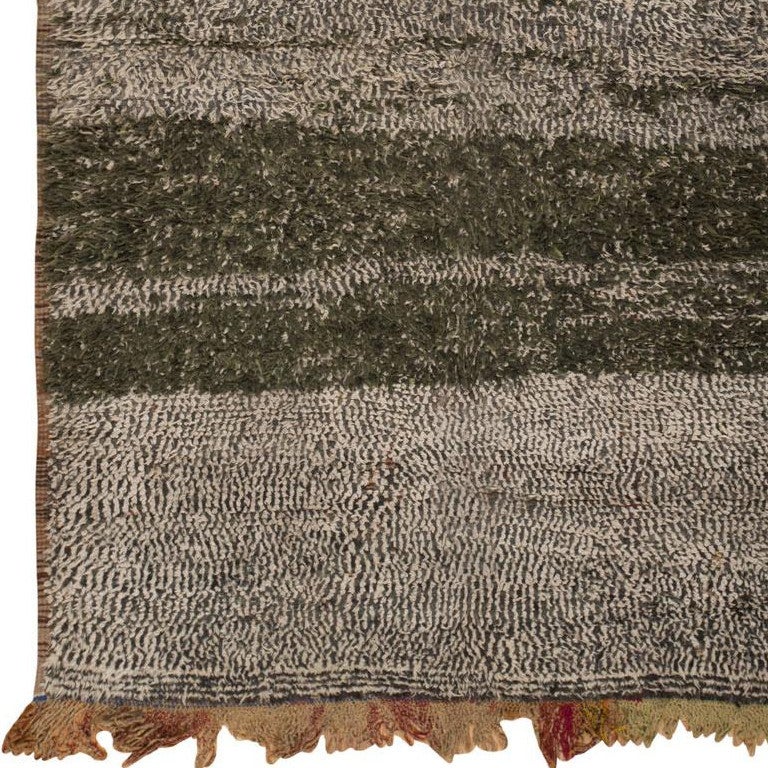 Created in Morocco circa 1950, this comely vintage Moroccan rug features a static allover pattern with stratified variegation and horizontal bands of darker streaks. The beautifully mottled pattern incorporates various shades of charcoal black and