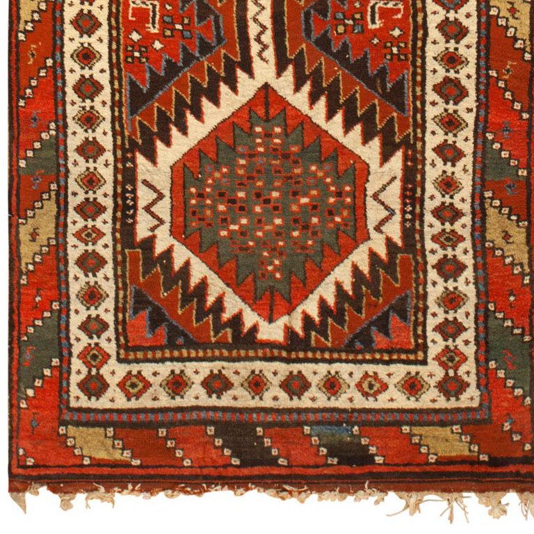 Created by Kurdish weavers, this spectacular antique Persian rug incorporates a rich variety of clear, high-contrast colors that are paired with geometric symbols and graphic accents. The impressive composition includes a pillar of stacked lozenges