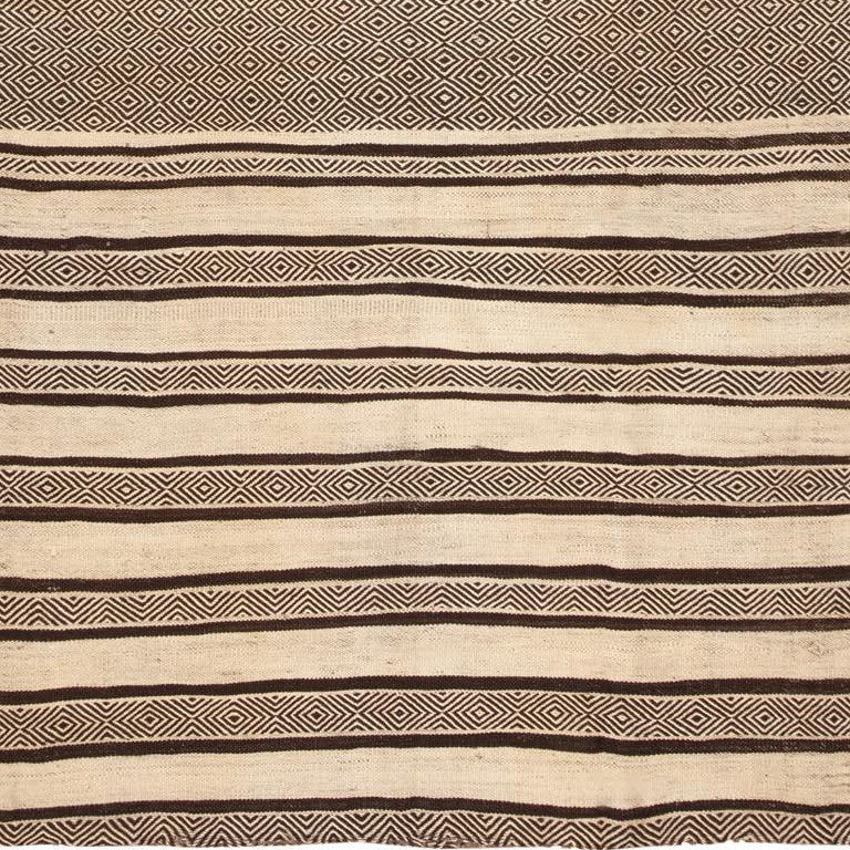 This vintage Mid-Century Moroccan Kilim highlights the inherent beauty and unassuming modernity of traditional weaving techniques and cultural motifs that have been handed down for thousands of years. These age-old techniques produce the tantalizing