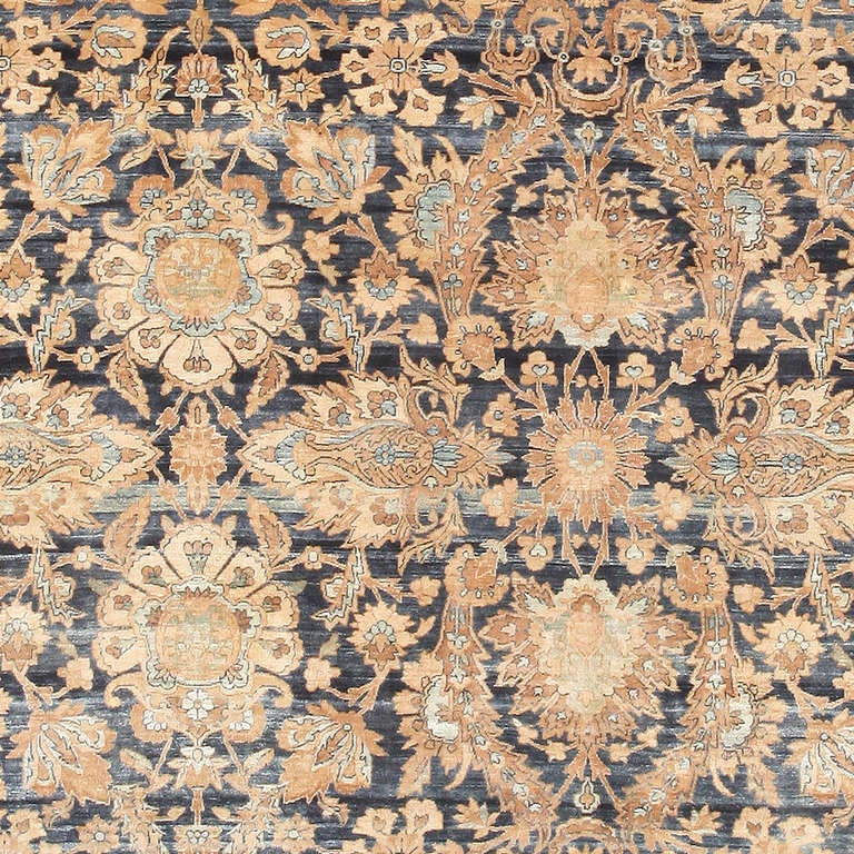Extraordinarily ornate, even by Kerman standards, this oversized antique Persian carpet features an exquisite repeating pattern with lacy gilt-yellow botanicals set over a regal midnight blue ground. This handsome filigree pattern displays a subtle