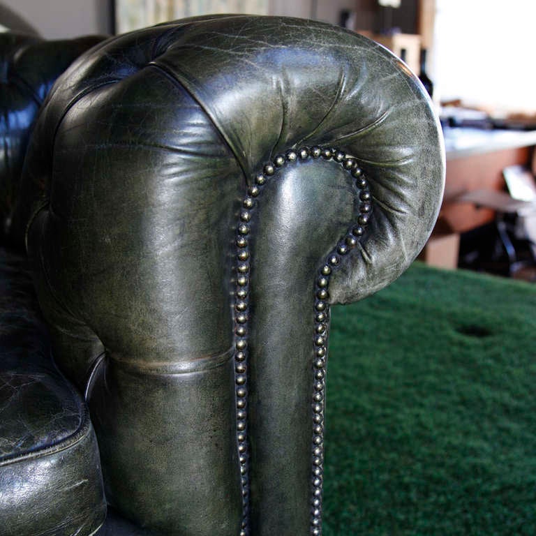Early 20th century English leather chesterfield sofa's. Deeply tufted green leather resting on four turned bun feet. Two available, $7,500 each.