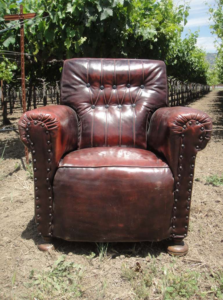 English button backed 1910's leather armchair with out scrolled arms.