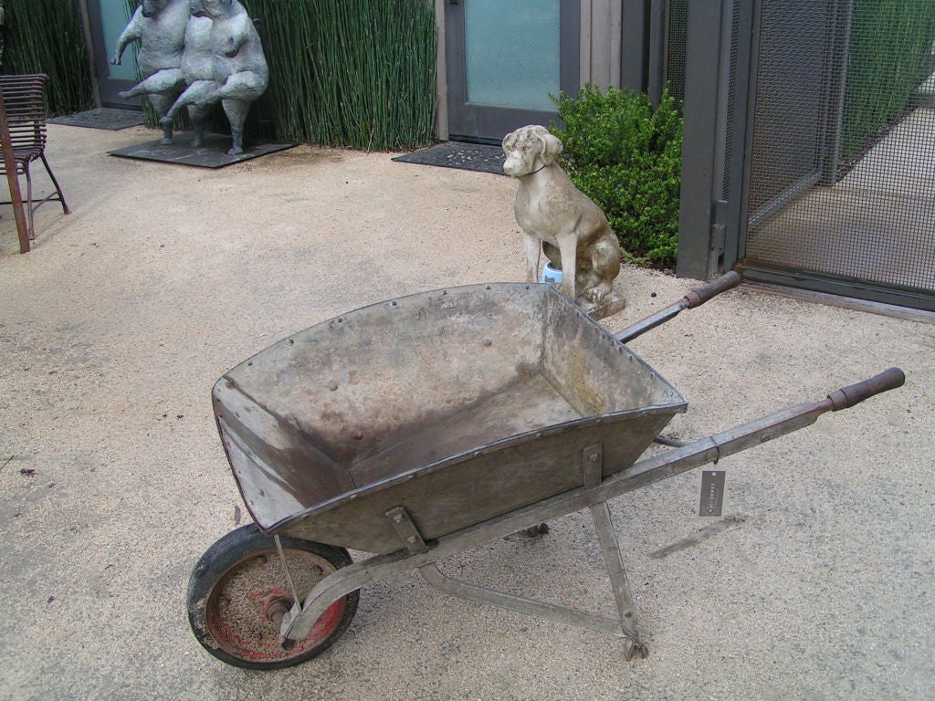 Gorgeous industrial-looking wheel barrow in great, solid condition.  Nice red wheel in front, rivets and wood handles.  Would look great on the patio with ice and some bottles of wine.