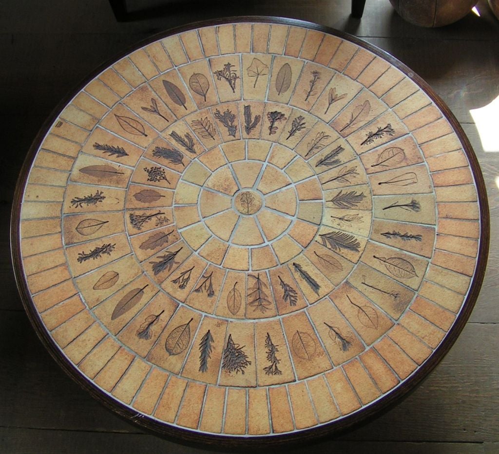 Circular Roger Capron coffee table.  Earth-tone tiles have impressions of various leaves arranged in pie sections around a center point.  One tile is stamped with "Capron Vallauris France".