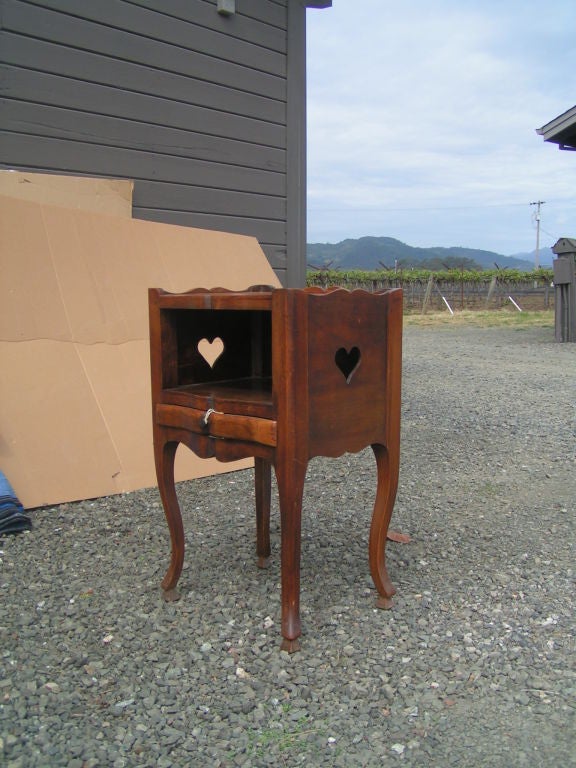 A pair of walnut side tables with carved heart cut-outs in excellent condition. Both tables are sturdy, with a few water marks on top surface. Carved heart cut-outs on the sides with a complementary bow motif.

Sold as a set.
   