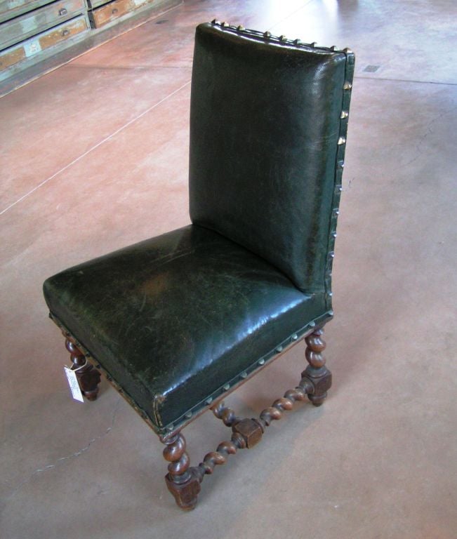 Set of four French dining chairs; green leather upholstery with studded ed ges and spiral turned wood bases.