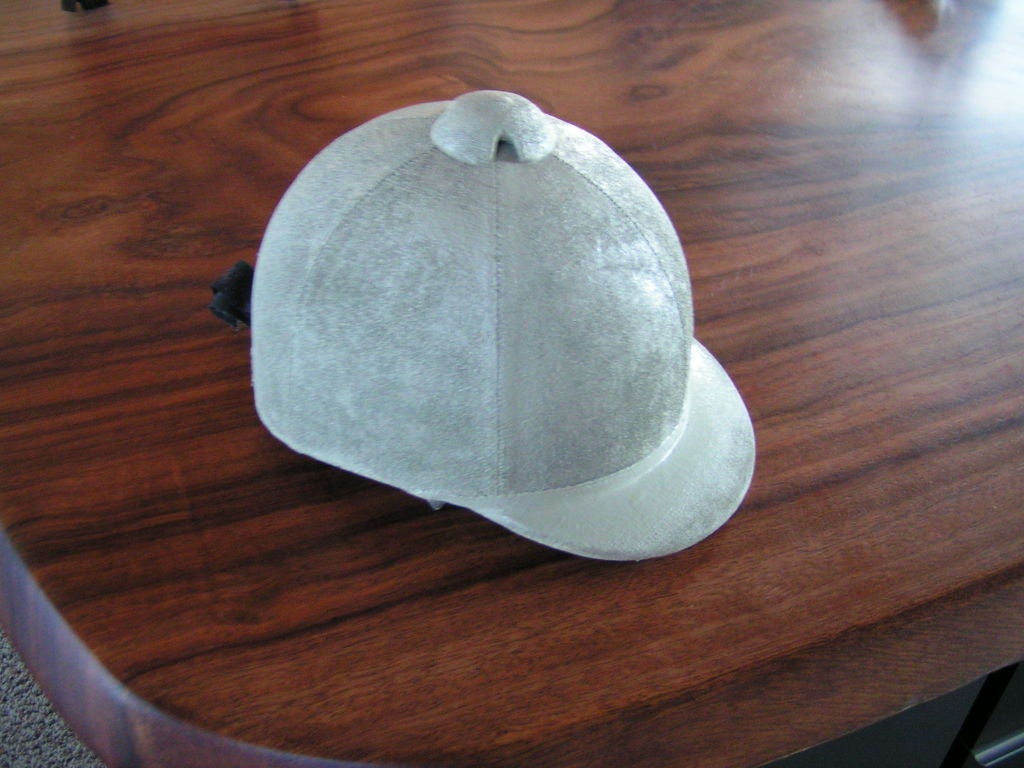 Cream colored child's riding helmet.  We think it was painted this color over the velvet.  Still has brown ribbon in back.  Definitely would make a unique decorative object.